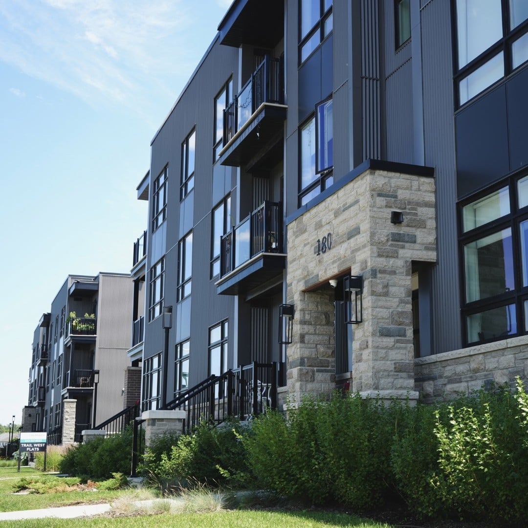 The exterior of a modern mid-rise apartment complex featuring sleek black siding and natural stone accents in Eastern Ontario.